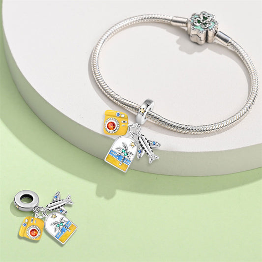 A triple-hanging pendant featuring an airplane, a yellow camera, and a backpack.